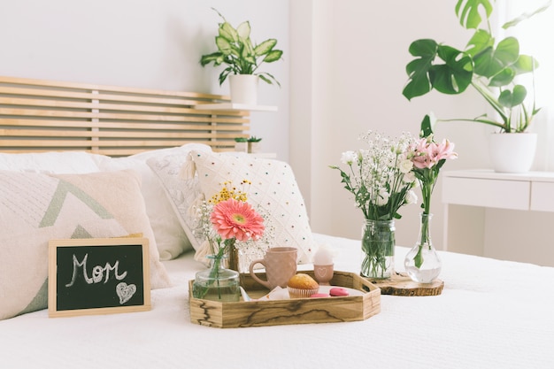 Mutteraufschrift mit Blumen und Bonbons auf Tablett