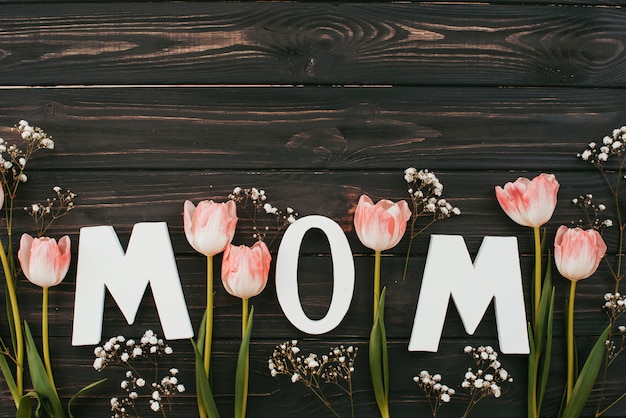 Mutteraufschrift mit Tulpen auf dunklem Holztisch