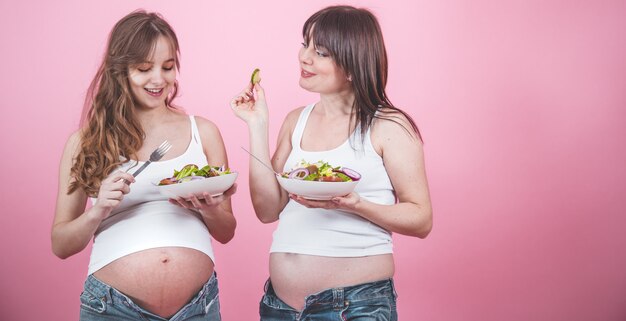 Mutterschaftskonzept, zwei schwangere Frau, die frischen Salat isst