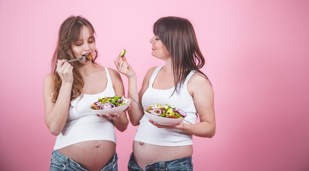 Mutterschaftskonzept, zwei schwangere Frauen, die frischen Salat essen