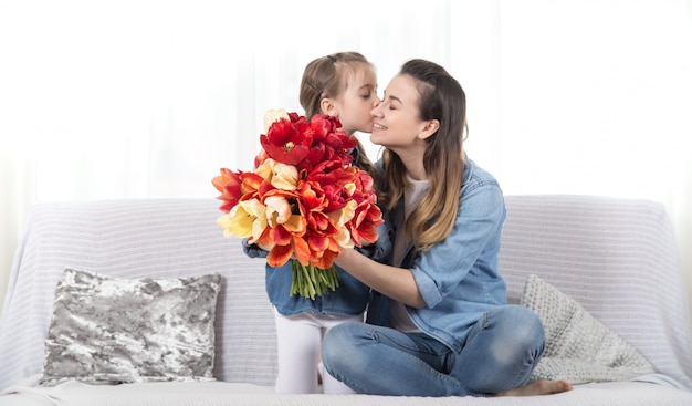 Muttertag. Kleine Tochter mit Blumen gratuliert ihrer Mutter