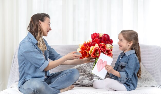 Muttertag. Kleine Tochter mit Blumen gratuliert ihrer Mutter