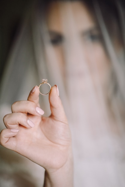 Mysteriöses Porträt einer Braut versteckt unter dem Schleier und einen Hochzeitsring halten