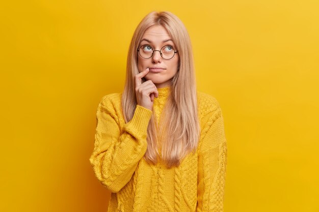 nachdenkliche blonde Frau konzentriert über tief in Gedanken tief trägt runde Brille lässigen Pullover