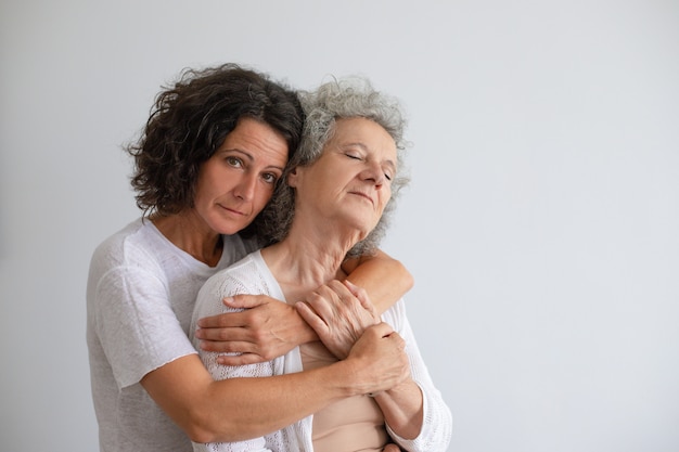 Kostenloses Foto nachdenkliche erwachsene tochter, die ältere mutter umarmt