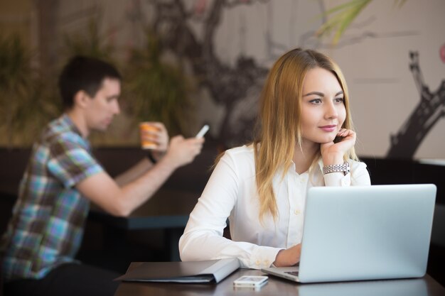 Nachdenkliche Geschäftsfrau in dem Coffee-Shop arbeiten