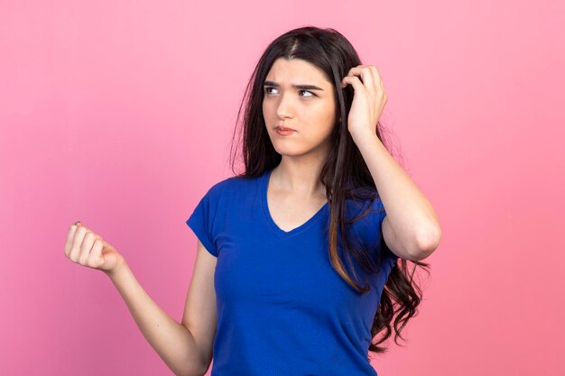 Nachdenkliche junge Dame, die auf rosafarbenem Hintergrund steht und denkt