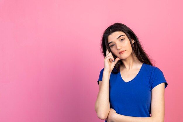 Nachdenkliche junge Dame, die ihre Hand an den Kopf hält und in die Kamera schaut Hochwertiges Foto