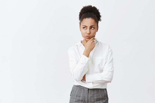 Nachdenkliche junge ernsthafte afroamerikanische Geschäftsfrau, die über Geschäftsideen nachdenkt