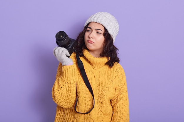 Nachdenklicher junger hübscher europäischer Mädchenfotograf, der moderne Kamera verwendet