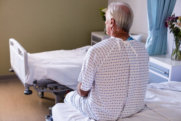 Nachdenklicher männlicher älterer Patient, der in der Station sitzt