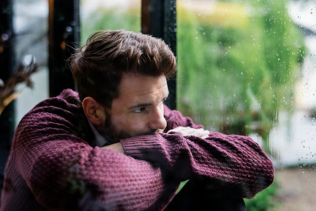 Kostenloses Foto nachdenklicher mann, der aus dem fenster schaut