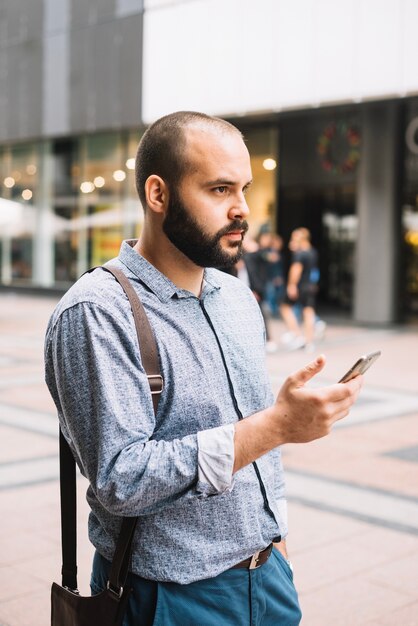 Nachdenklicher Mann, der draußen Telefon verwendet