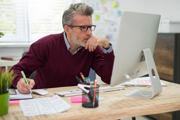 Nachdenklicher Mann, der hart am Computer arbeitet