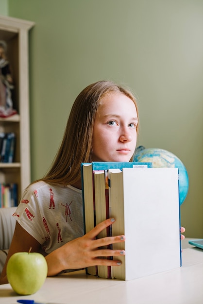 Nachdenklicher Schüler mit gestapelten Büchern