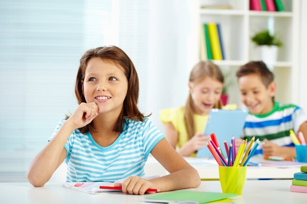 Nachdenkliches kleines Mädchen in einem Klassenzimmer sitzen