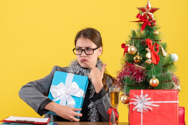 Nachdenkliches nachdenkliches Mädchen mit Brille, die am Tisch sitzt und Finger setzt