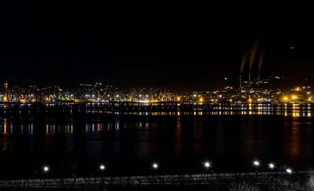 Nachtpanoramablick auf die Hafenkräne und andere Hafeninfrastruktur Novorossiysk-Handelshafen an der Tsemesskaya-Bucht des Schwarzen Meeres