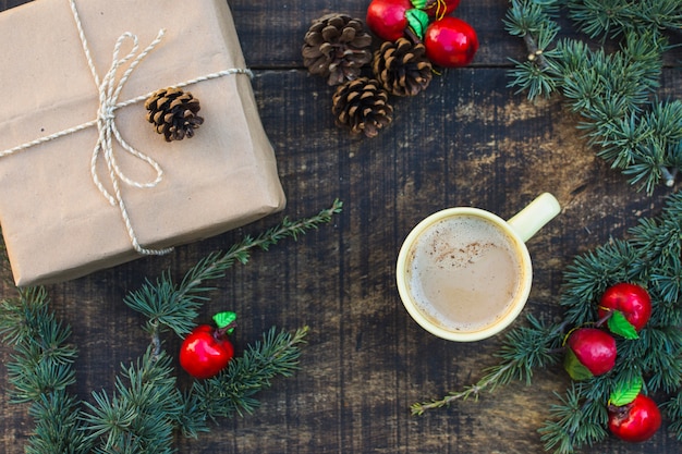 Nadelbaumkegel und gefälschte Äpfel nahe Geschenk und Kaffee