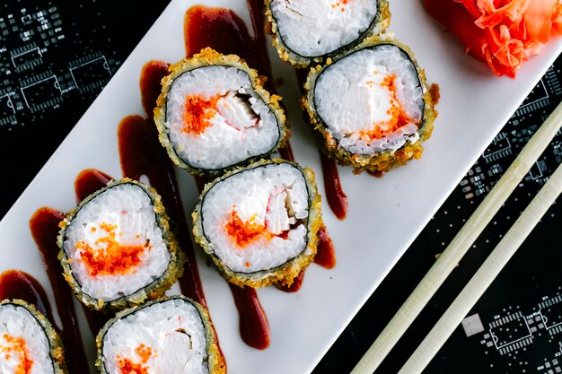 Nahansicht der heißen Sushi-Rollen mit rotem Tobiko und Krabbenstab