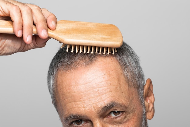 Nahaufnahme älterer Mann, der Haare bürstet