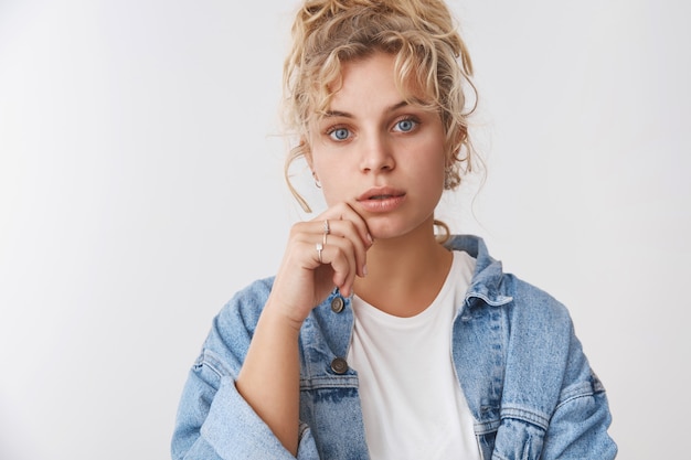 Nahaufnahme attraktive nachdenklich fokussierte faszinierte junge Studentin, die interessanten Vortrag mit offenem Mund interessiert, Blick blaue Augen Kamera zuhört, Lippe neugierig stehende weiße Wand berühren