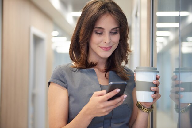 Nahaufnahme auf Frau, die Kaffee trinkt und das Telefon bedient