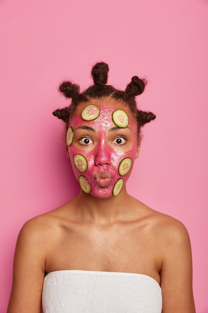 Nahaufnahme auf glückliche ethnische Frau genießt das Anwenden der Gesichtsmaske isoliert
