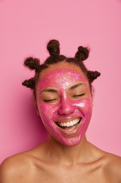 Nahaufnahme auf glückliche ethnische Frau genießt das Anwenden der Gesichtsmaske isoliert