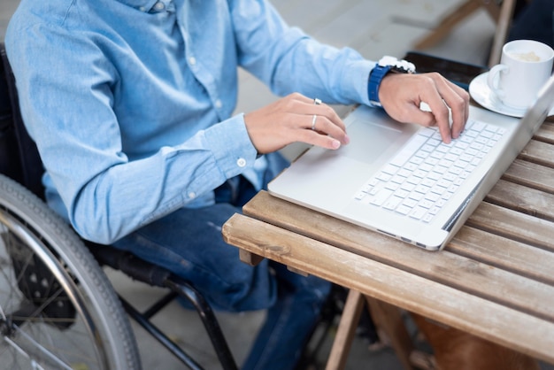 Kostenloses Foto nahaufnahme behinderter mann, der auf laptop schreibt