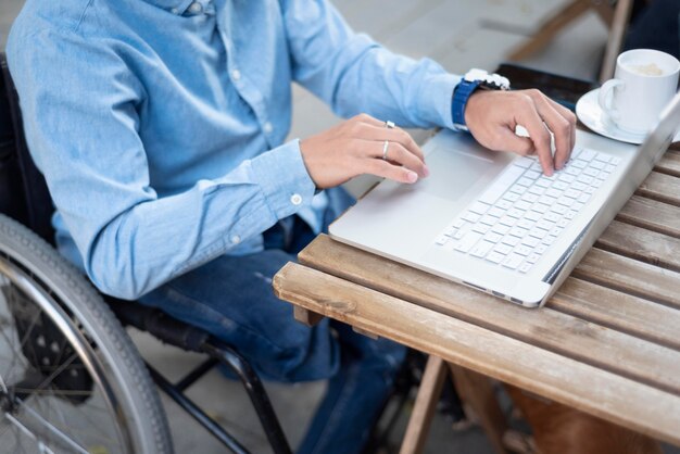 Nahaufnahme behinderter Mann, der auf Laptop schreibt