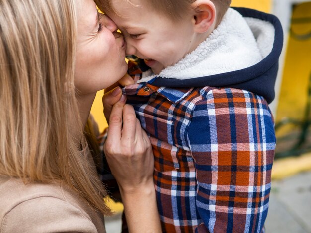 Nahaufnahme blonde Mutter, die ihren Jungen küsst