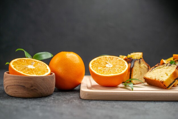 Nahaufnahme der Ansicht der frischen Zitronenscheiben und der frisch gebackenen gehackten Kuchenscheiben auf dunklem Tisch