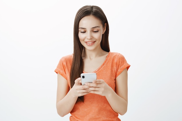 Nahaufnahme der attraktiven jungen Frau, die Handy, Nachrichten oder Anwendungsanwendung verwendet