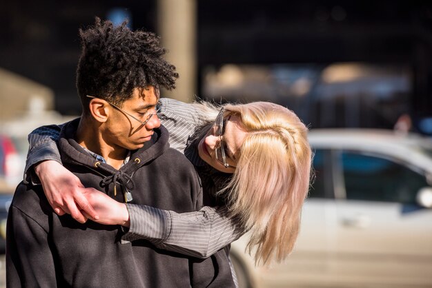 Nahaufnahme der blonden jungen Frau, die seinen afrikanischen Freund umarmt