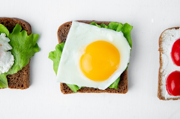 Nahaufnahme der Brotscheibe mit Eigelb-Holland-Käse und Spinat auf Weiß