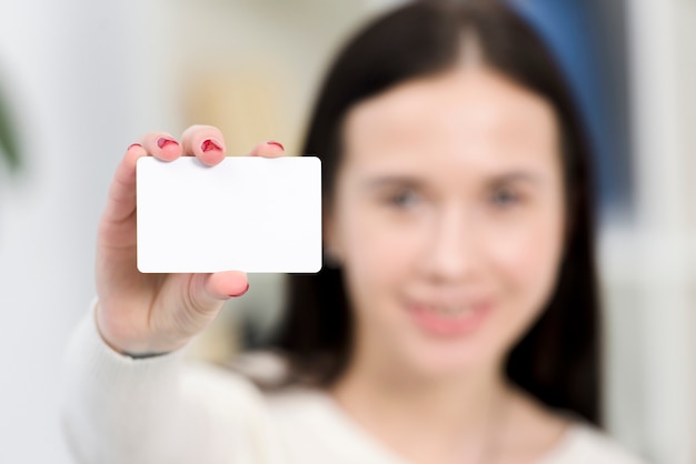 Nahaufnahme der defocus jungen Geschäftsfrau, die weiße Visitenkarte zeigt