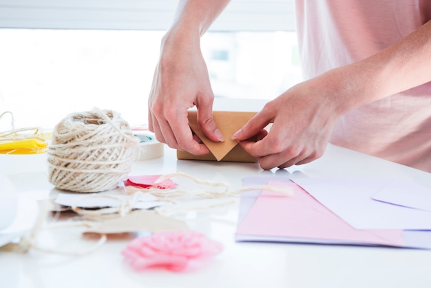 Nahaufnahme der Frau die Geschenkbox auf Tabelle einwickelnd