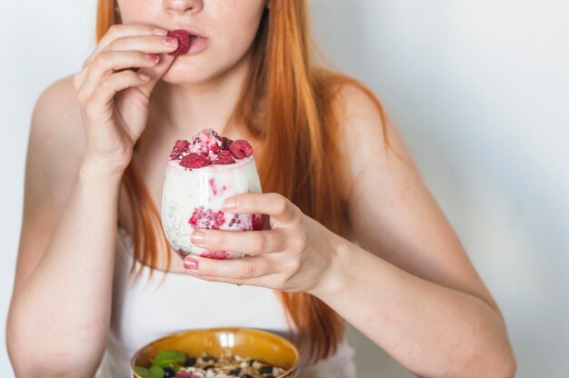 Nahaufnahme der Frau Himbeere vom Joghurt essend