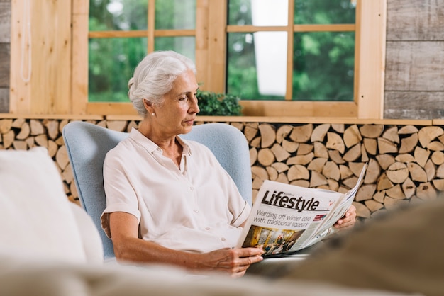 Nahaufnahme der Frau sitzend auf Stuhllesezeitung