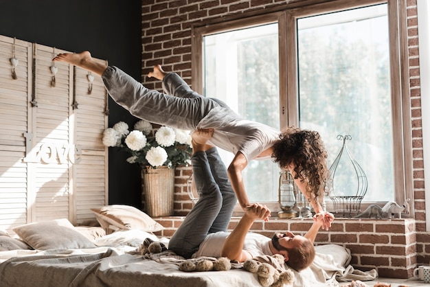 Nahaufnahme der Füße eines balancierenden Mannes der Frau auf Bett zu Hause
