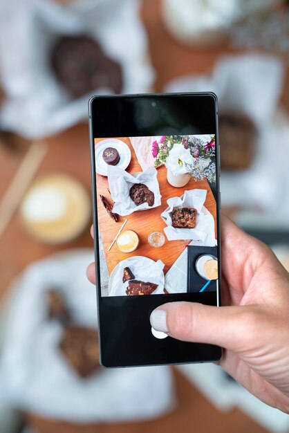 Nahaufnahme der Hände, die Cupcake-Fotos machen