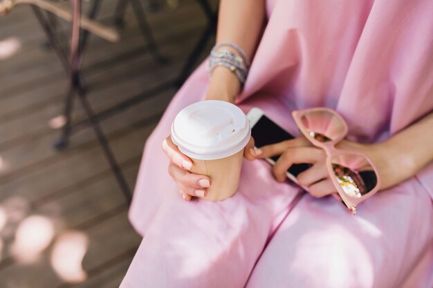 Nahaufnahme der Hände einer Frau, die im Café im Sommermode-Outfit sitzt