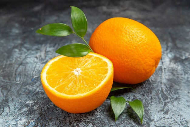 Nahaufnahme der halbierten und ganzen frischen Orange mit Blättern auf grauem Hintergrund stockfoto