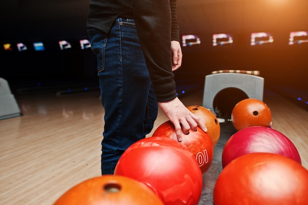 Nahaufnahme der Hand des Bowlingspielers, die den roten Ball aus dem Schüssellift nimmt