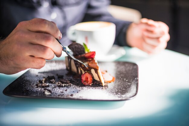 Nahaufnahme der Hand des Mannes, die Kuchen mit Gabel isst