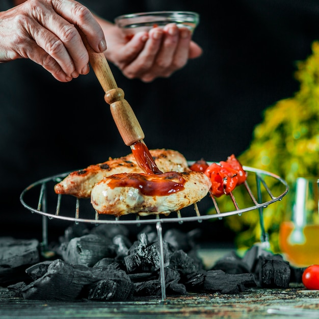 Nahaufnahme der Hand, die Soßenbad auf bbq-Fleisch bürstet