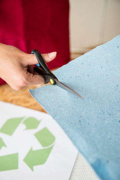 Kostenloses Foto nahaufnahme der hand einer frau, die blaues papier mit scheren schneidet