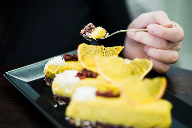 Nahaufnahme der Hand einer Frau, die Kuchen mit Löffel isst