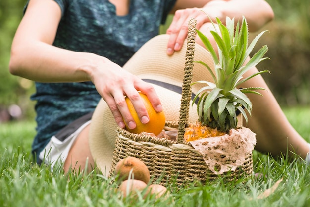 Kostenloses Foto nahaufnahme der hand einer frau mit dem korb, der orange frucht hält